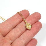 handheld image of little golden tortoise charm necklace