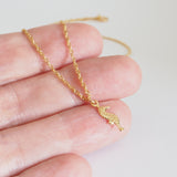 tiny gold seahorse charm necklace photo on finger to show size