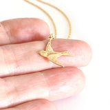 gold swallow charm necklace photographed on finger to show the size