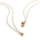 Close up Super Petite Gold Bauble Necklace next to larger size necklace
